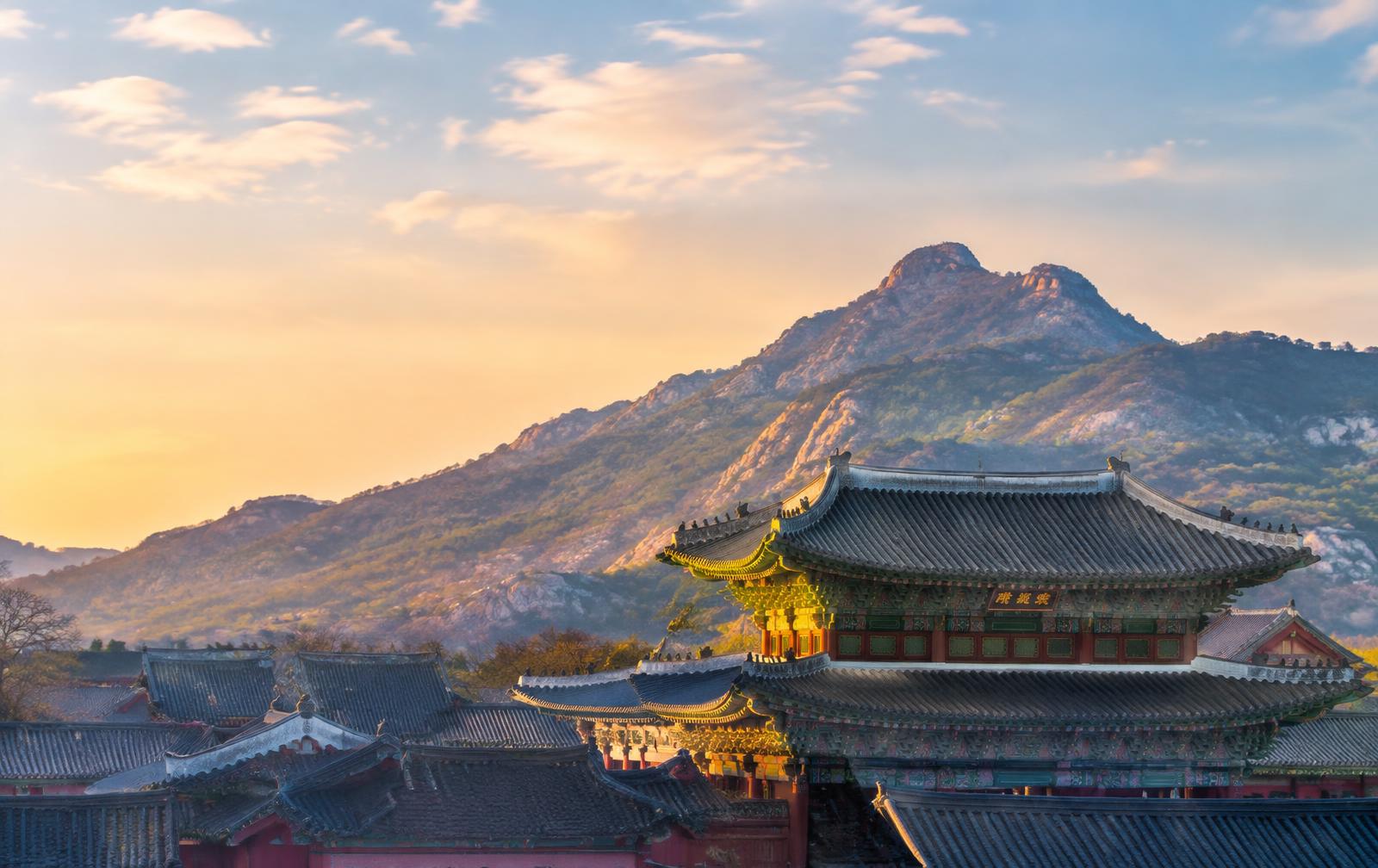 Palace rooftops beneath mountains in Seoul